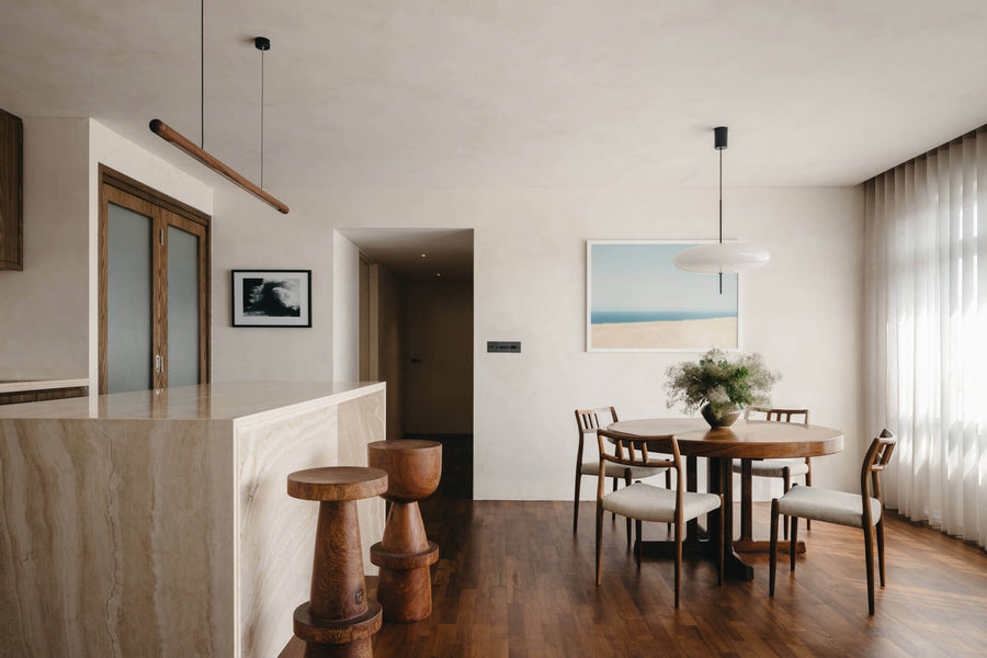 A waterfall stone island sits in the foreground along with two modern wood barstools and wood flooring finished with Rubio Monocoat hardwax oil wood finish.