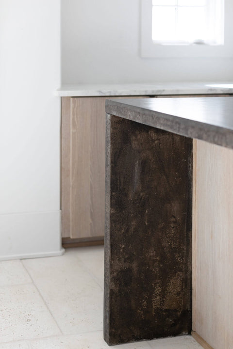 Detail photo of white oak kitchen island with dark waterfall counter tops.