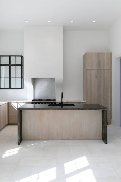 White kitchen with light wood island and dark countertop.