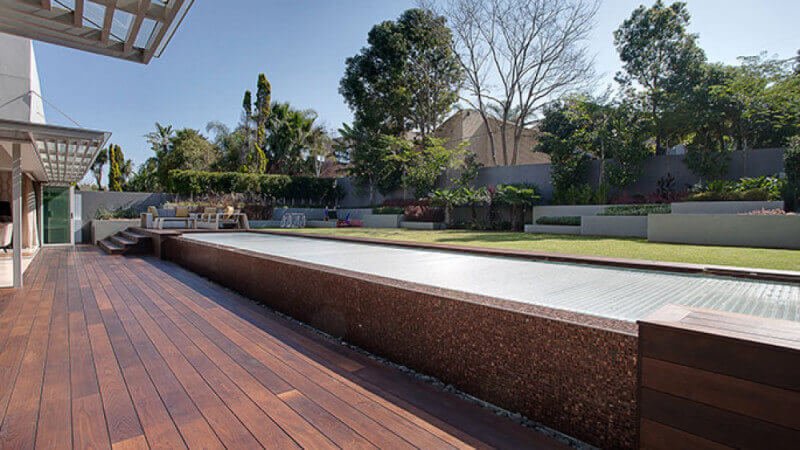 A backyard with a wood deck and a raised grass yard.