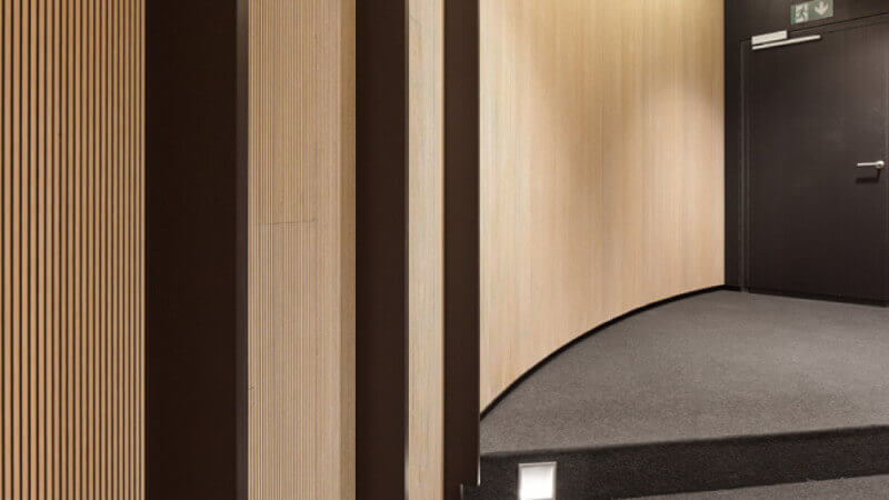 A curved wall of acoustical panels made from wood finished with Rubio Monocoat hardwax oil wood finish.