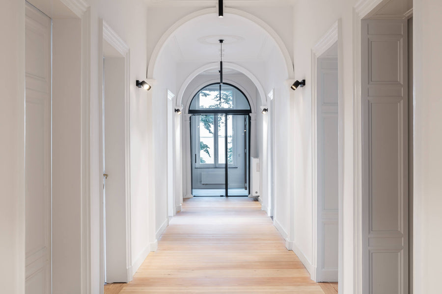A arched hallway with wood flooring finished with Rubio Monocoat hardwaxoil  leads to an arched glass door.