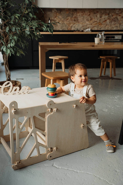 A child kneels next to a toddler learning tower transformed into a table for a safe yet functional play time.