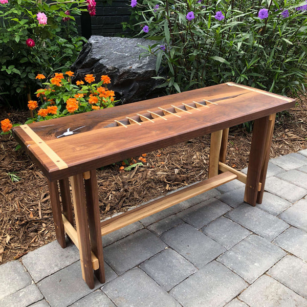 Overhead view of a walnut bench inlaid with hard maple pieces featuring mortise and tenon joinery.