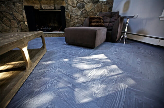 A living room with herringbone wood flooring that has accented wood grain.