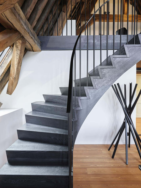 Curving black wood staircase.