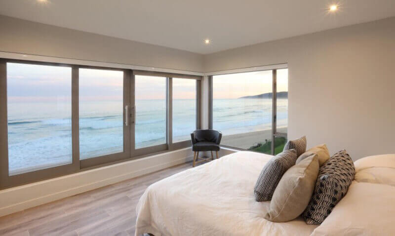 Bedroom overlooking the ocean with hardwood flooring.