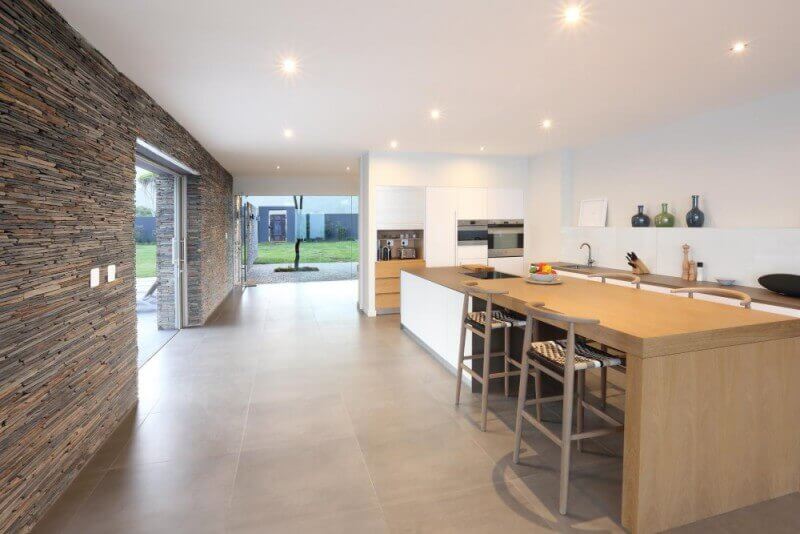 Inside an open space kitchen design with a kitchen island and wood dining table combo.