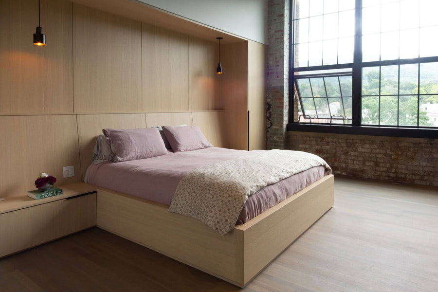 New York loft bedroom with hardwood flooring and a wooden bed frame and headboard.
